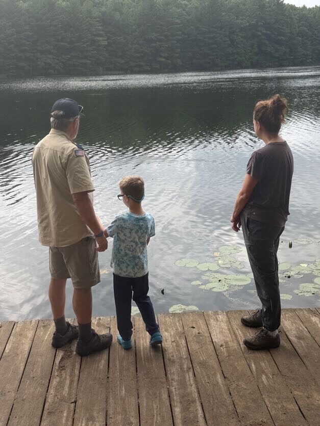 Scout fishing at the lakeshore with two adults nearby
