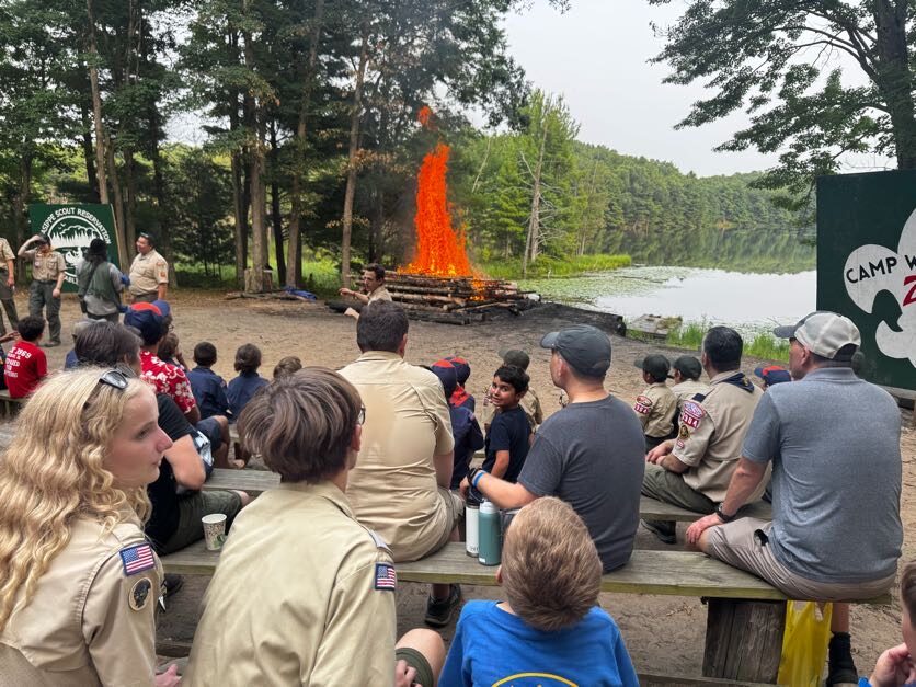 Scouts and families watching a campfire beside the lake