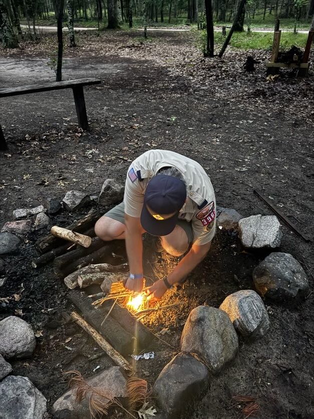 Scout tending a small campfire in a stone fire ring