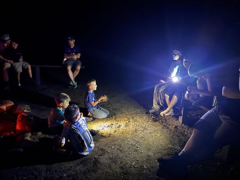 Pack members seated around an evening campfire